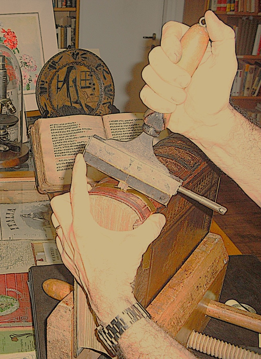 Restauro a mano su libro antico, con strumenti su misura.
